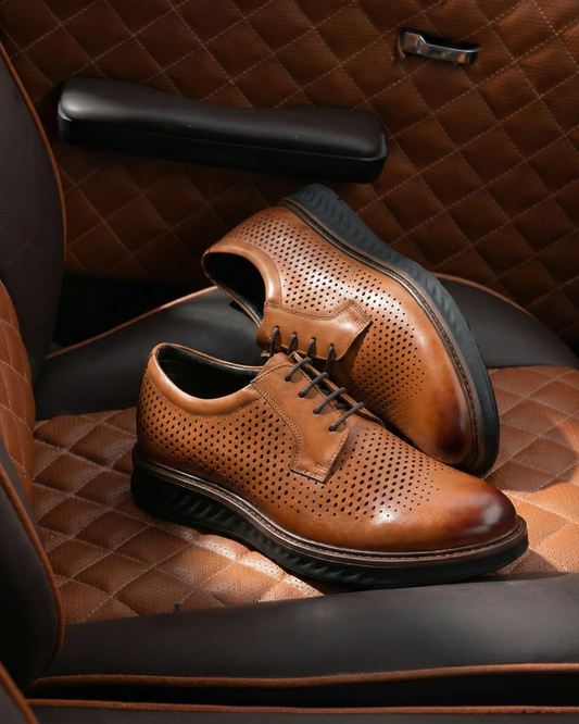 Tan perforated Derby shoes on luxury quilted leather chair showing premium office footwear